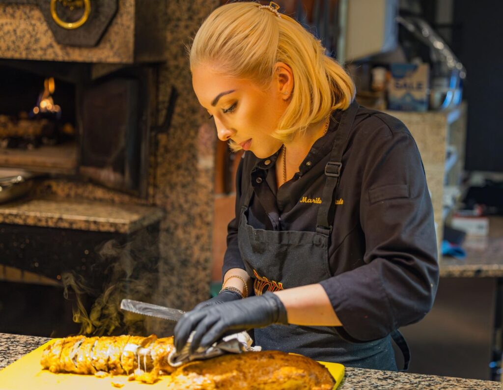 Kochkurs in Leipzig: Marilù Natale schneidet ein dampfendes Gericht frisch aus dem Holzofen des Ristorante Don Giovanni an